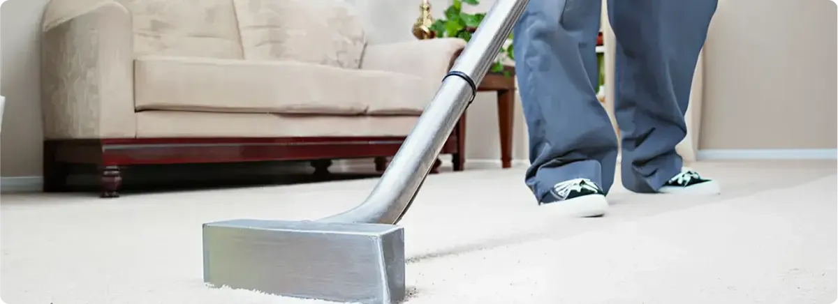 Carpet cleaning technician using a hot-water extraction wand on a light-colored carpet in a living room, Allentown, PA.