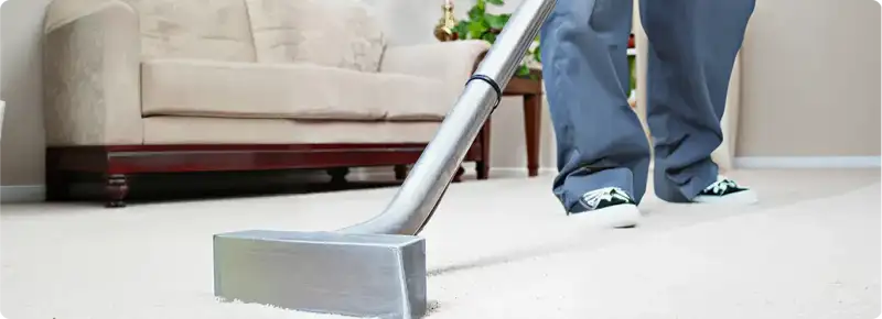 Carpet cleaning technician using a hot-water extraction wand on a light-colored carpet in a living room, Allentown, PA.