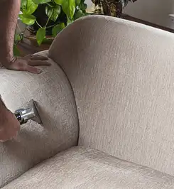 Professional upholstery cleaner deep-cleaning a fabric sofa with a handheld extraction tool and hose Allentown, PA.